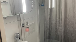 A bathroom with a white sink, toilet, and shower area. - Anita Hostel (Zürich)