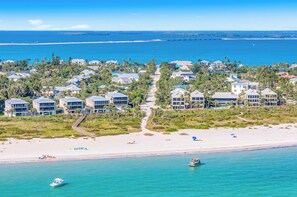 An aerial view of a coastal resort with beachfront villas, a sandy beach, and clear blue waters. - Seahorse Suites #2. Fun,Beach, Games, Memories! (Sanibel)