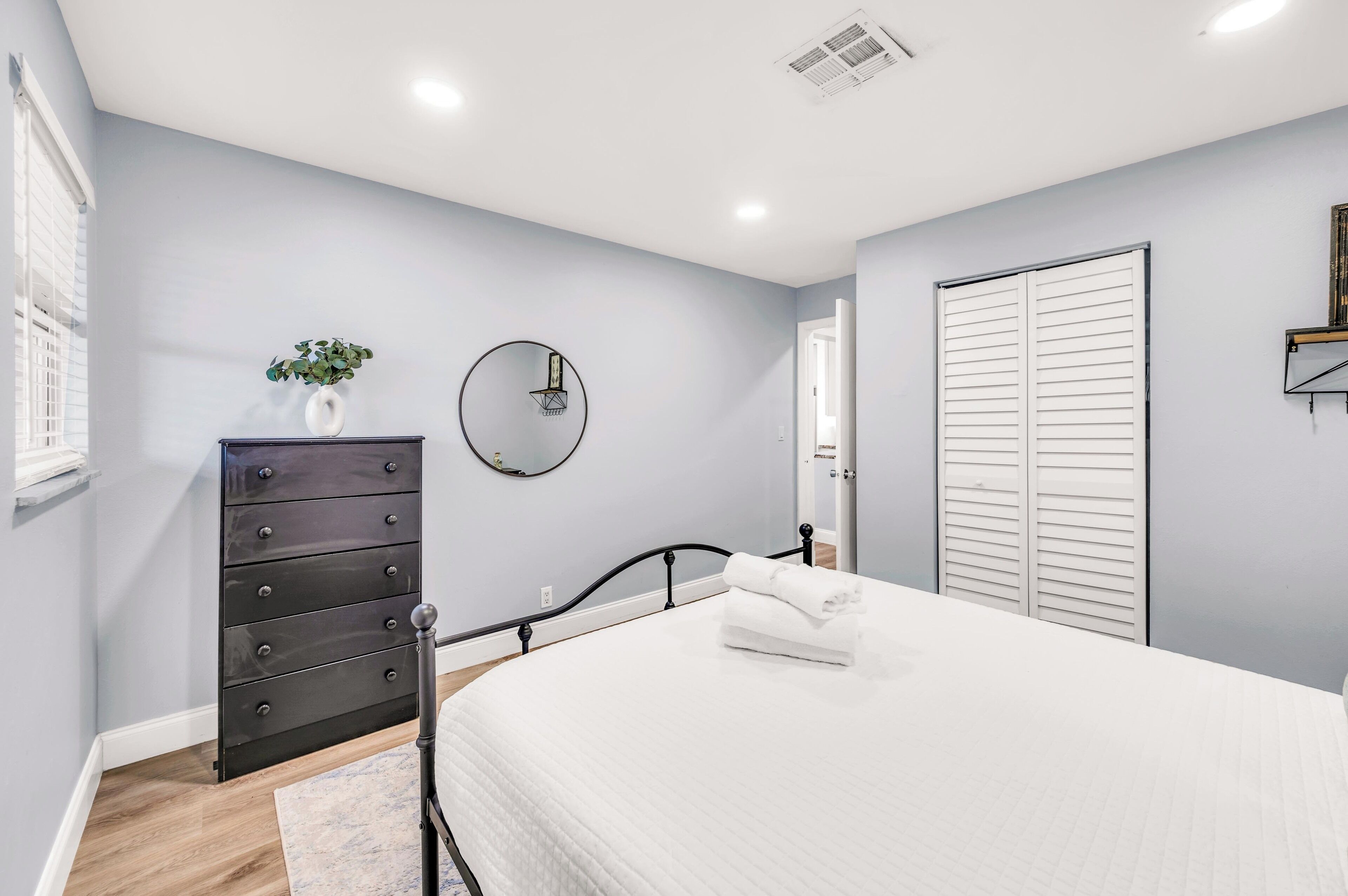 A bedroom with a bed, a dresser, a mirror, and a door.