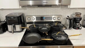 A kitchen with a stainless steel range, a coffee maker, a toaster, and pots on the stove. - Stylish New Home, Near Shops, WiFi, 2V Garage, Smart TV, Private Yard, Near ✈️. (Edmonton)