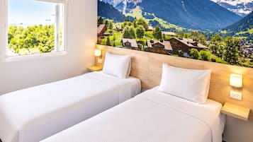 Habitación de hotel con dos camas, un ventanal grande y un mural en la pared con paisaje de montaña.