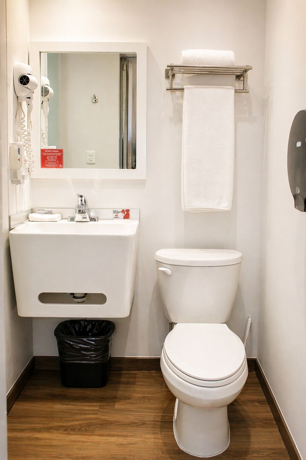 A small bathroom with a toilet, sink, and hair dryer.
