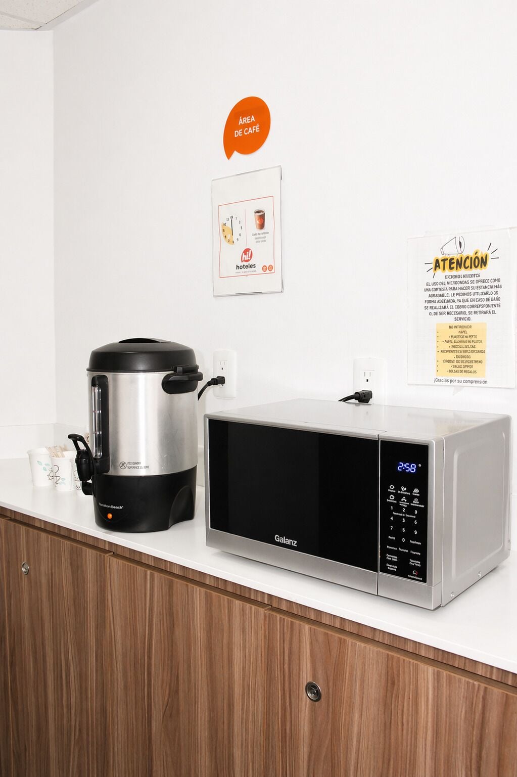 A kitchenette with a coffee maker, a microwave, and a coffee cup on the counter.