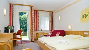 A hotel room with a bed, a desk, a chair, a TV, and a view of the outdoors. - Stadthotel Raabs an der Thaya (Raabs An Der Thaya)