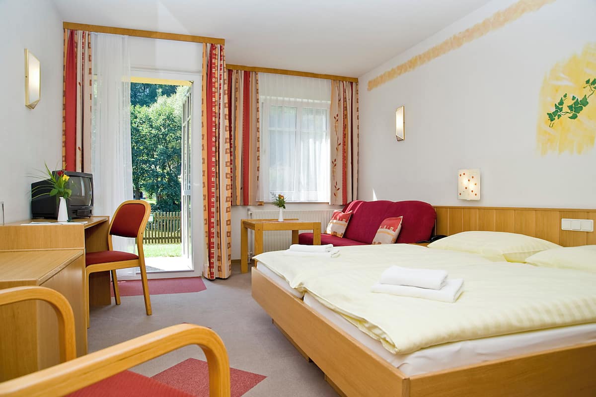 Une chambre d’hôtel équipée d’un lit, d’un bureau, d’une chaise, d’une télévision et offrant une vue sur l’extérieur.