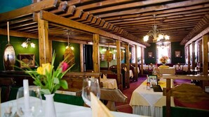 A restaurant with wooden beams, green walls, and tables set for dining. - Stadthotel Raabs an der Thaya (Raabs An Der Thaya)