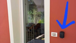 Una puerta con un panel de vidrio, un felpudo y un portero automático en la pared.