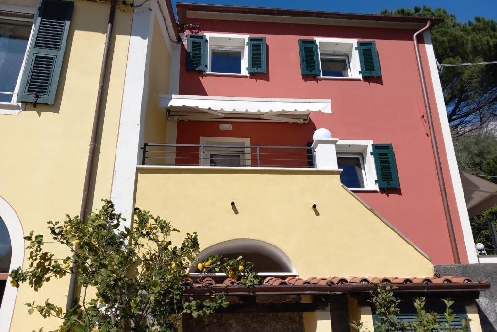 Ein zweistöckiges Gebäude mit roter Fassade, weißem Zierrat und grünen Fensterläden.