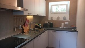 Una cocina moderna con electrodomésticos de acero inoxidable, armarios blancos y un ventanal con cestas en el alféizar.