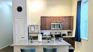 A modern kitchen with a central island, stainless steel appliances, and wooden cabinets.