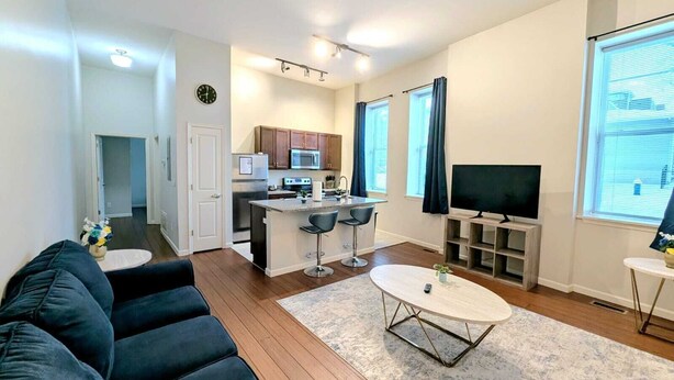 A modern living room with a dark-colored sofa, a coffee table, and a TV on a stand.