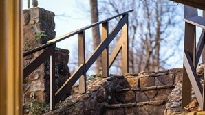 Kivestä rakennettu portaikko, jossa on metallikaiteet, johtaa kiviseen muuriin.