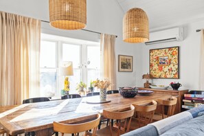 Comedor con una mesa de madera, sillas y lámparas de mimbre colgantes.