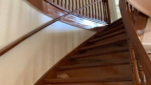 A wooden staircase with a handrail and a curved wall.