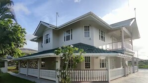 A two-story house with a covered porch and a fenced yard.