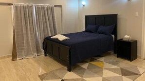 A bedroom with a bed, a nightstand, and a geometric-patterned rug.