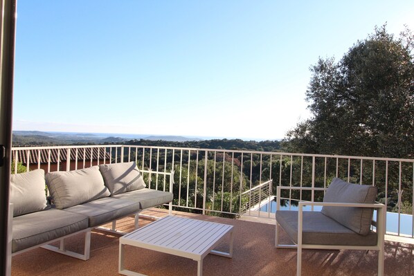 Enjoy the serene view from this balcony, which offers a comfortable seating area with a sofa and table.