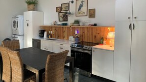 Eine moderne Küche mit Essbereich, ausgestattet mit Herd, Spüle und weißen Schränken.
