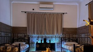 A room with a bed, a table with a decorative item, a curtain, and patterned walls.