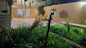 An outdoor area with a table and chairs, a palm tree, and a building with a satellite dish.