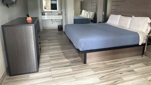A modern hotel room with a large bed, a desk, a flat-screen TV, a bathroom with a mirror, and a wardrobe. - Blue Diamond Inn (Houston)