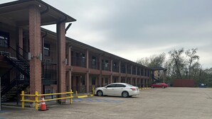 A multi-story building with a covered entrance and a parking lot. - Blue Diamond Inn (Houston)
