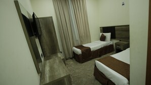 Una habitación de hotel con dos camas, suelo de madera, televisor y cortina.