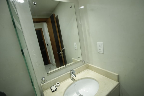 Un baño con un lavabo blanco, un espejo y una puerta al fondo.