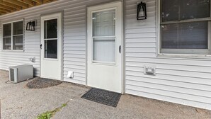 A single-story building with a covered porch, white siding, and multiple windows. - Cozy 1BR in Winooski! (Winooski)