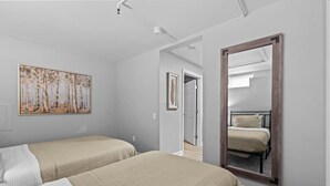 A bedroom with two beds, a large mirror, and a painting on the wall. - Cozy 1BR in Winooski! (Winooski)