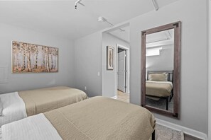 Een slaapkamer met twee bedden, een grote spiegel en een schilderij aan de muur.