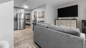 A modern living room with a grey sofa, a flat-screen TV, and a fireplace. - Cozy 1BR in Winooski! (Winooski)