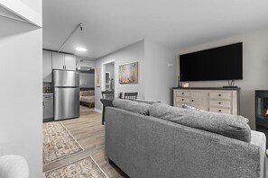 Een moderne woonkamer met een grijze bank, een flatscreen televisie en een open haard.