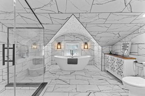 Ein modernes Badezimmer mit freistehender Badewanne, einer Duschkabine aus Glas und einem Waschtisch mit Spiegel und Beleuchtung.