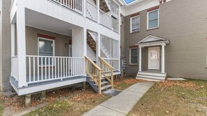 A two-story residential building with a front porch, a staircase, and a small front door. - Unique Top-Floor Apt in BTV (Burlington)