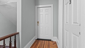 A hallway with a wooden floor, white walls, and a closed door with a number '3' above it. - Unique Top-Floor Apt in BTV (Burlington)