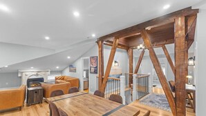 A loft-style living space with a dining area, a fireplace, and a staircase with exposed wooden beams. - Unique Top-Floor Apt in BTV (Burlington)
