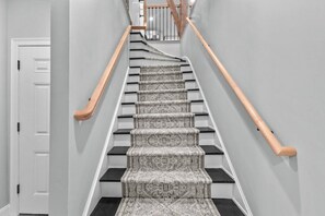 A staircase with patterned carpet, wooden handrails, and a white door at the bottom.