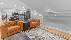 A modern apartment with a dining area, two sofas, a kitchen, and a staircase leading to an upper level. - Unique Top-Floor Apt in BTV (Burlington)
