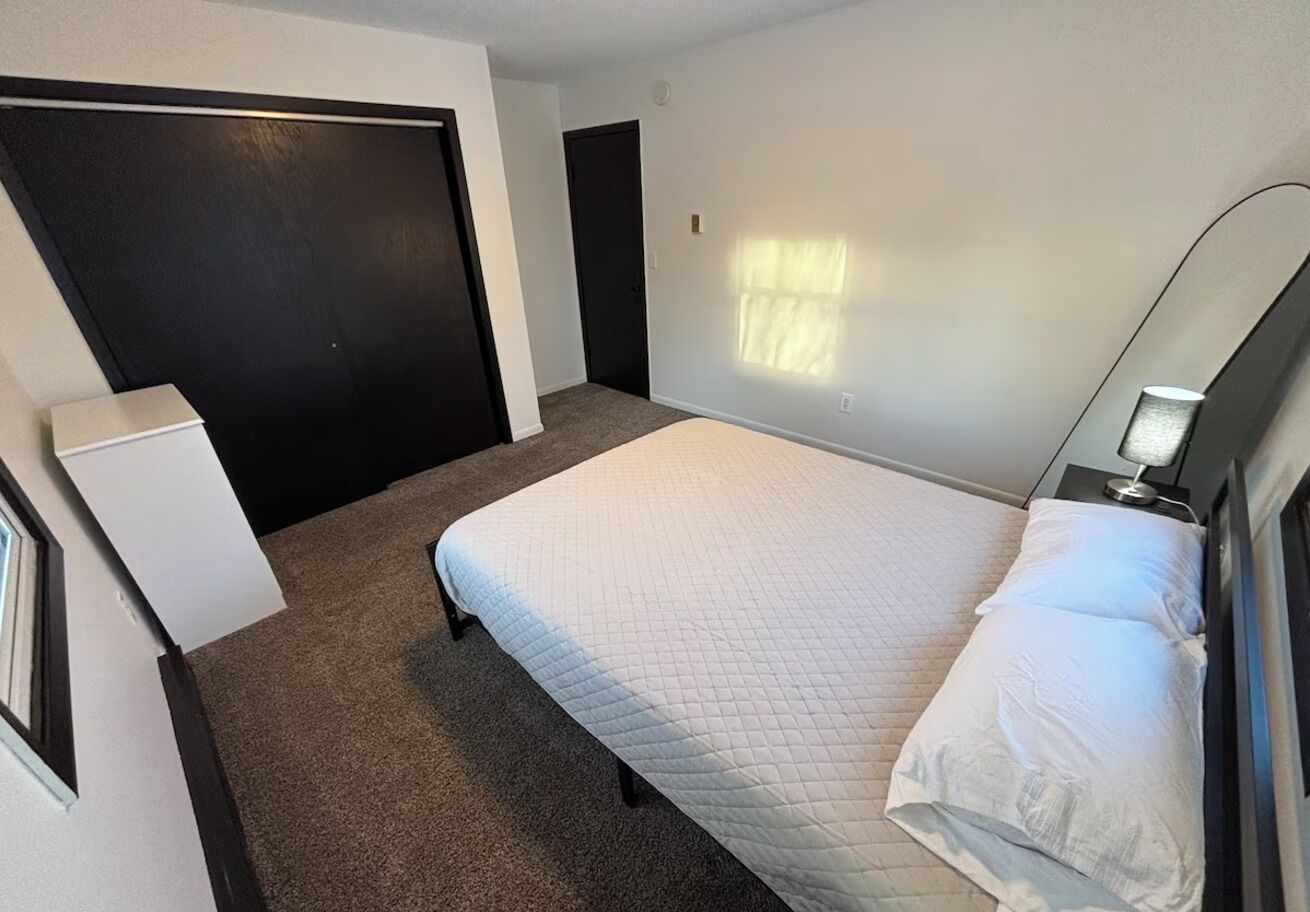 Ein Schlafzimmer mit Bett, Nachttisch, Kommode und Tür.