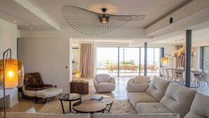 Un salon spacieux comprenant un grand canapé, une table basse et un coin repas avec des chaises.