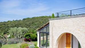 Un bâtiment moderne en pierre, doté d’une porte en verre et d’un petit balcon.