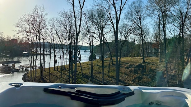 A hot tub with a view of a lake and trees. - Family-Friendly Lakefront Home with Hot Tub, Firepit, Dock & Breathtaking Views! (Charlotte)