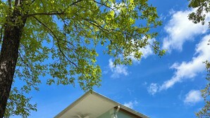 A two-story house with a covered porch, a staircase leading to the entrance, and a clear blue sky. - Family-Friendly Lakefront Home with Hot Tub, Firepit, Dock & Breathtaking Views! (Charlotte)