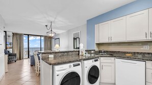 A modern kitchen with built-in appliances, a dining area with a view, and a laundry room. - 3 BR Palms Resort: Oceanfront (Myrtle Beach)
