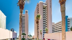 A high-rise building with the name "PALMS" on its facade, surrounded by palm trees and other buildings. - 3 BR Palms Resort: Oceanfront (Myrtle Beach)