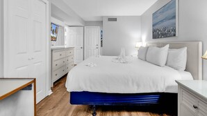 A bedroom with a large bed, white walls, and a painting. - 3 BR Palms Resort: Oceanfront (Myrtle Beach)