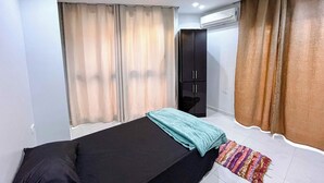 A bedroom with a bed, a wardrobe, an air conditioning unit, and curtains.