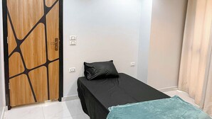 A bedroom with a bed, a wooden door with a geometric design, and a light-colored wall.