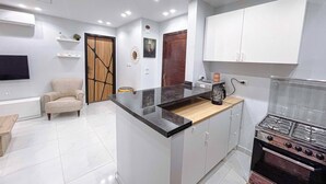 A modern kitchen with a central island, built-in oven, and white cabinetry.